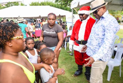 Minister of Tourism, Hon Edmund Bartlett (R) engaging with children ahead of the toy distribution by Santa (L) at the Christmas Treat held by the Ministry of Tourism and its public bodies at Harmony Beach Park in Montego Bay on Sunday, December 22, 2024.