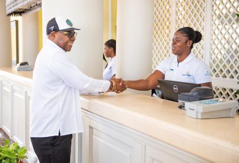 Minister Bartlett (L) greets a hotel front desk worker (R). 