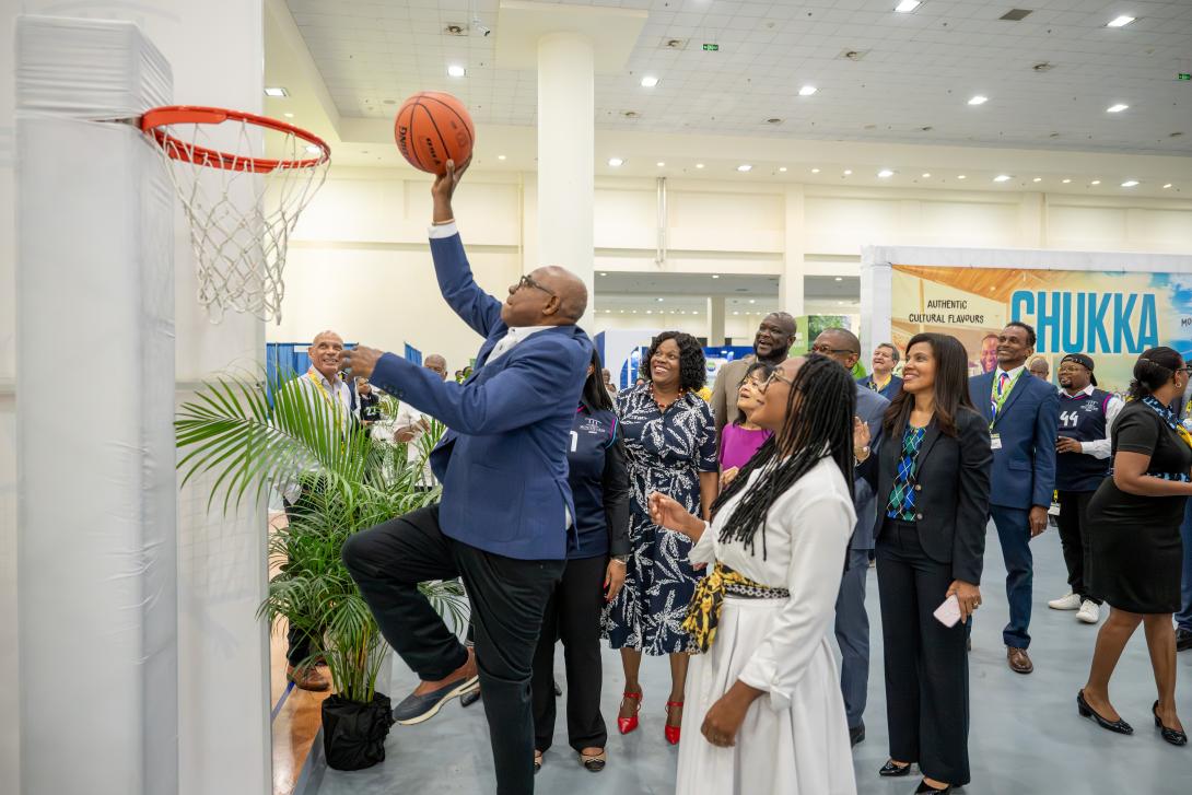 Minister Bartlett shoots at basketball at the hoop during his JAPEX 2025 trade floor walkthrough. 