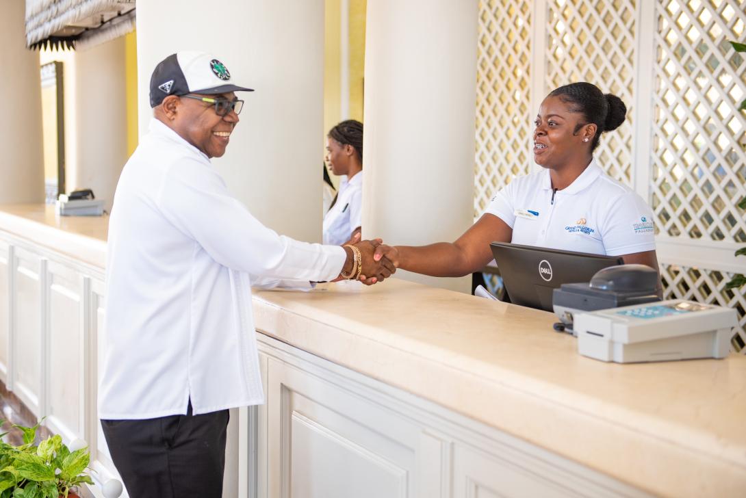 Minister Bartlett (L) greets a hotel front desk worker (R). 