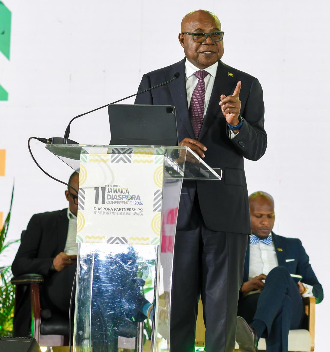 Minister of Tourism, Hon Edmund Bartlett addresses members of the Jamaican Diaspora and urges them to invest in Jamaica’s tourism industry and be its ambassadors. He was leading a panel discussion at the 11th Biennial Jamaica Diaspora Conference at the Montego Bay Convention Centre on Tuesday, June 16, 2026. Partly hidden (seated at left), is Director of Tourism, Donovan White and at right, Permanent Secretary in the Ministry of Water, Environment and Climate Change, Mr. Wayne Robertson.